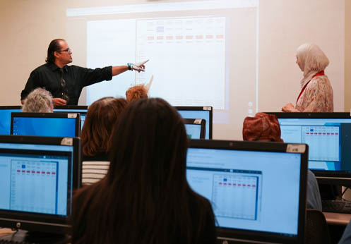 The instructor speaking towards the students pointing at the white board