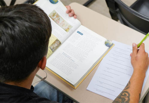 High school diploma student reading his textbook and taking notes