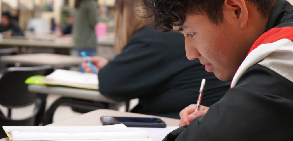 A photo of the NOCE student look down at his notebook, writing his notes.