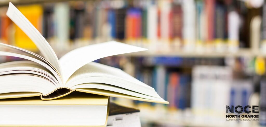 Textbooks open with more books in the background