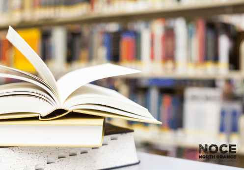 Textbooks open with more books in the background