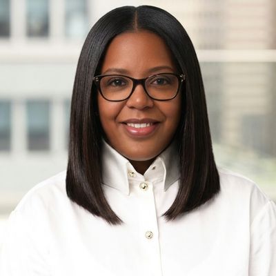 Tina McClurkin professional headshot wearing white button-up shirt and glasses, smiling at camera